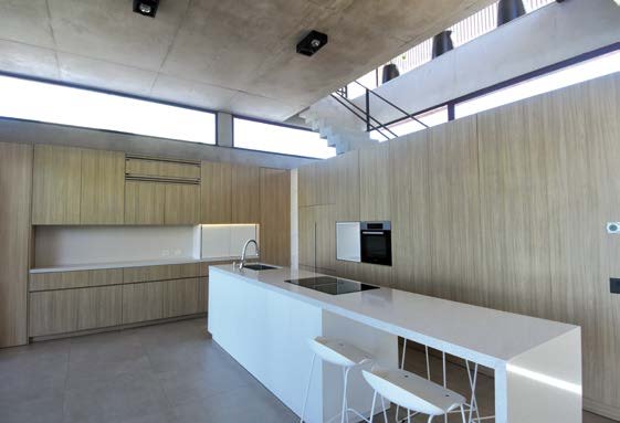 Casa Acacias: Cocina con isla, mobiliario de madera y cielorraso de hormigón visto